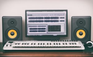 Home studio d'enregistrement avec enceintes de monitoring professionnelles et clavier MIDI.