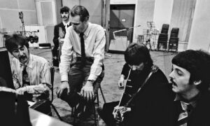 A photo of George Martin coaching the Beatles.