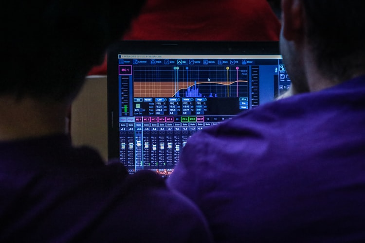 A photo of two people looking at a readout of an equalizer. In this article we discuss my favorite equalizers for electronic music.