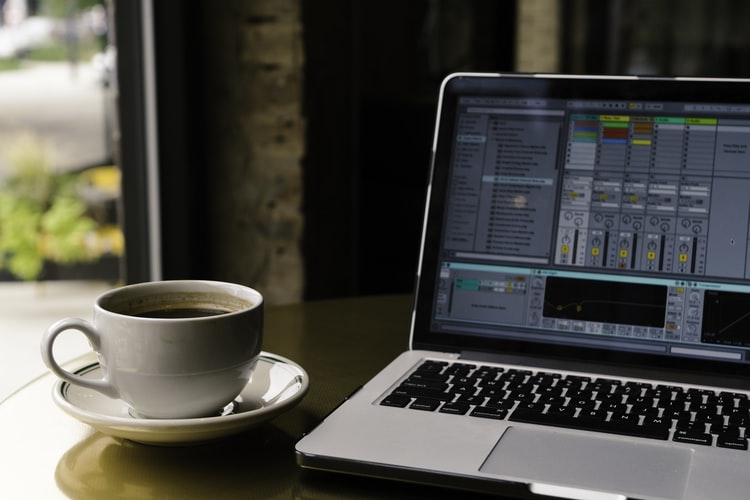 A photo of Ableton next to a cup of coffee.